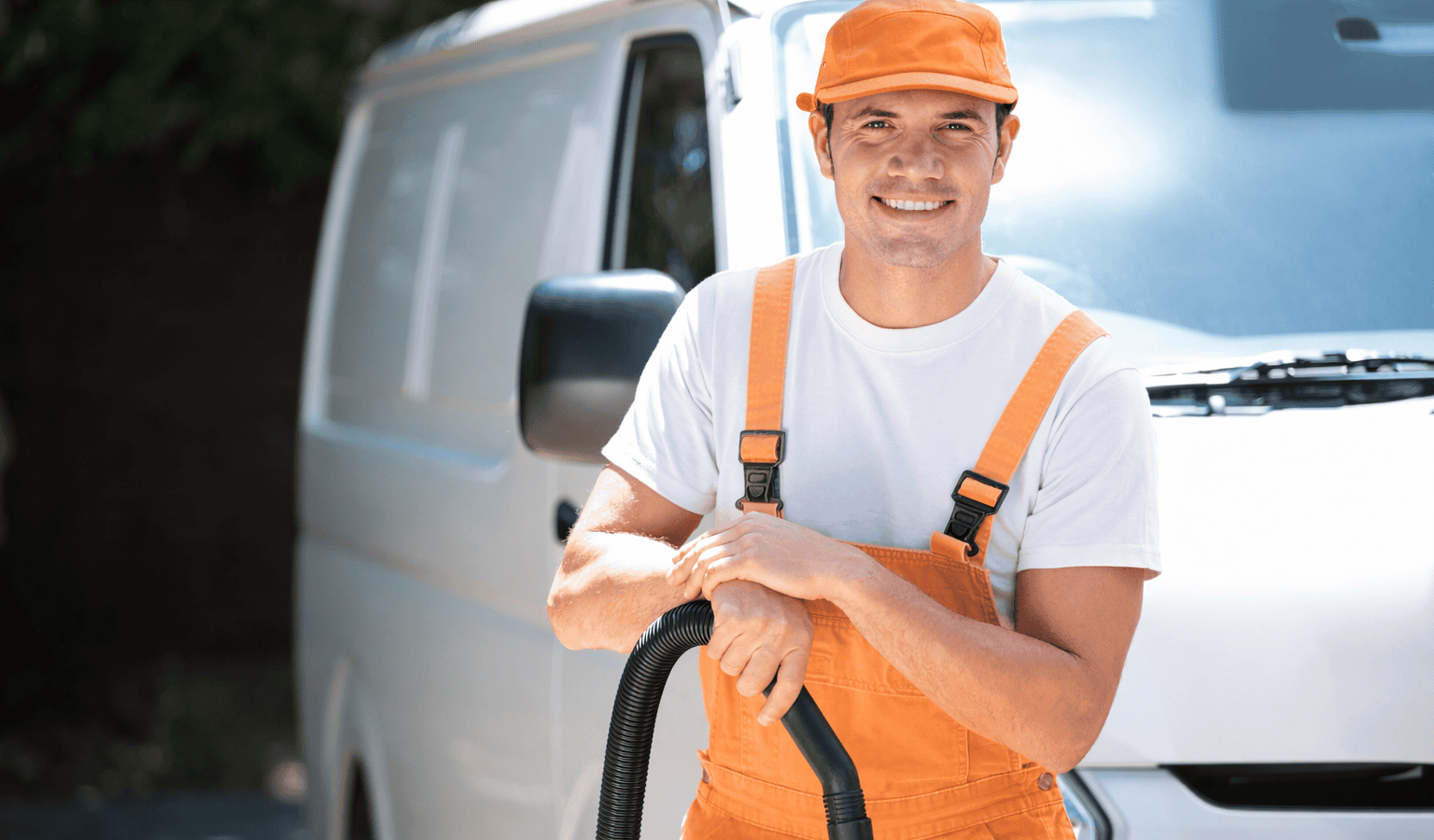Arbeiter steht mit Staubsauger vor einem Transporter